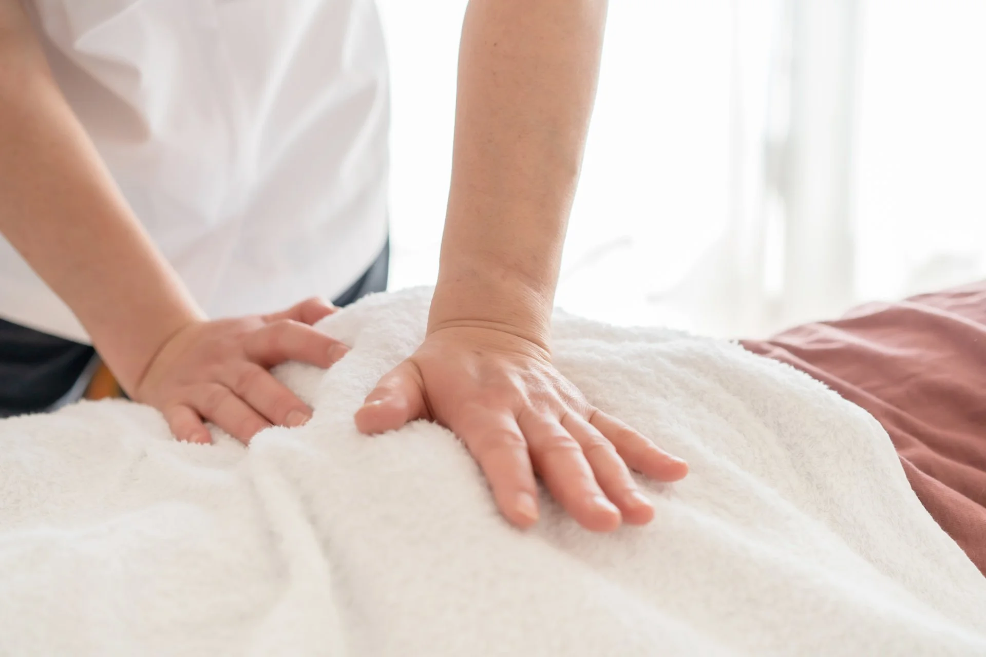 右側の縦長パネルに入る、静かな施術室で腰まわりの手技を行う施術の場面